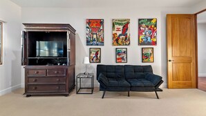 A living room with a TV stand, a sofa, and comic book art on the wall. - Krisyn Vineyards by Avantstay Private Pool + Spa Templeton Wine Country (Templeton)