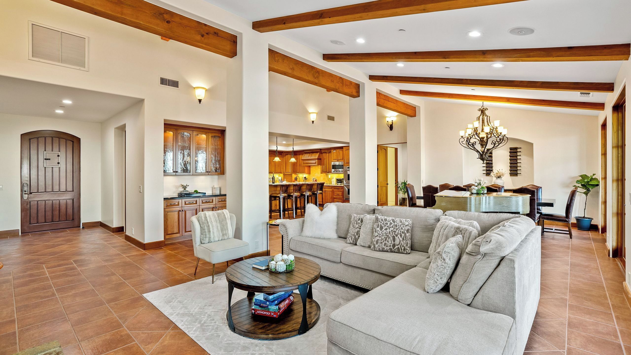 A spacious living area with a large sectional sofa, a coffee table, and a kitchen in the background.