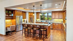 A spacious kitchen with a central island, wooden cabinets, and a large window providing a view of the outdoors. - Krisyn Vineyards by Avantstay Private Pool + Spa Templeton Wine Country (Templeton)