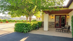 A building with a covered patio area, a stone wall, and a view of a vineyard in the background. - Krisyn Vineyards by Avantstay Private Pool + Spa Templeton Wine Country (Templeton)
