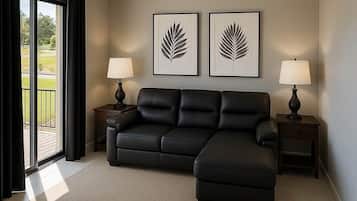 A modern living room with a sectional sofa, two side tables with lamps, a ceiling fan, and two framed leaf artworks on the wall.