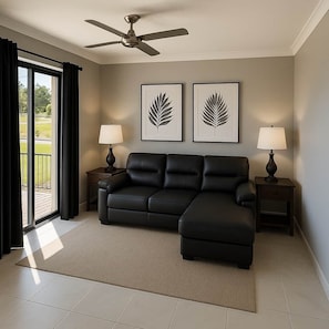 A modern living room with a sectional sofa, two side tables with lamps, a ceiling fan, and two framed leaf artworks on the wall. - Holiday House near Theme Parks (Pimpama)