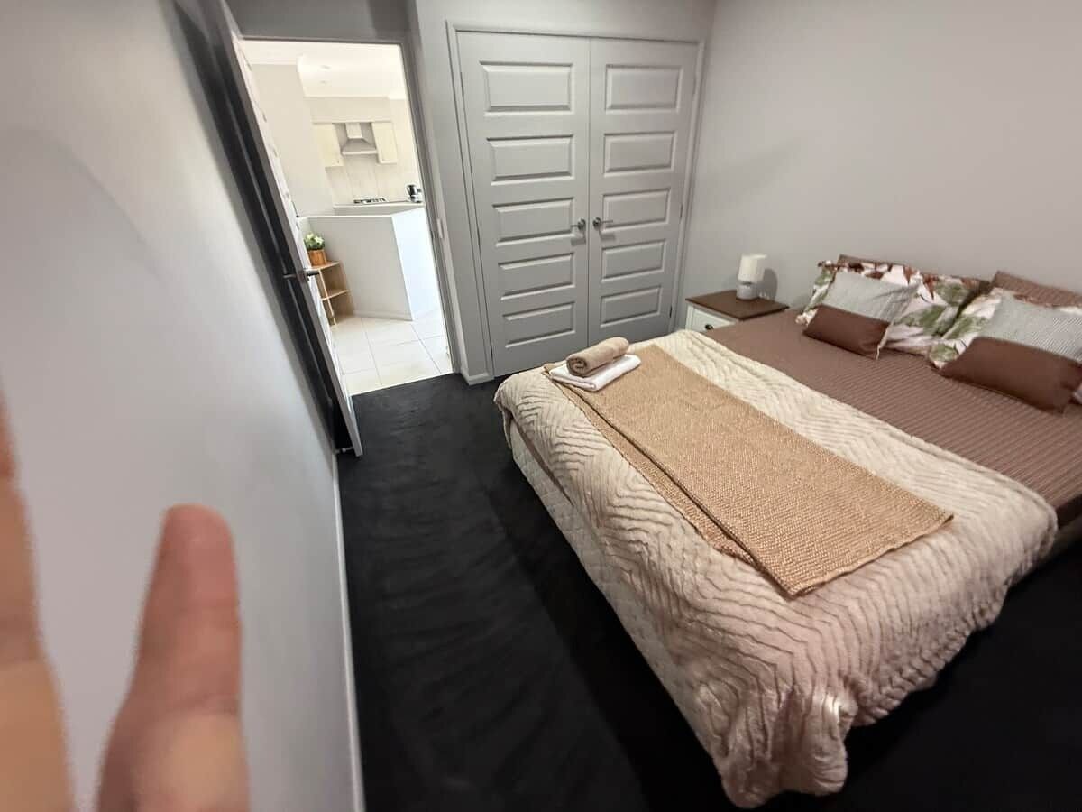 A bedroom with a bed, a nightstand, a wardrobe, and a bathroom visible through an open door.