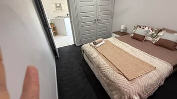 A bedroom with a bed, a nightstand, a wardrobe, and a bathroom visible through an open door.