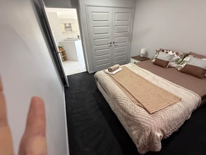A bedroom with a bed, a nightstand, a wardrobe, and a bathroom visible through an open door. - Holiday House near Theme Parks (Pimpama)
