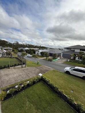 A residential area with houses, a paved road, and a grassy area.