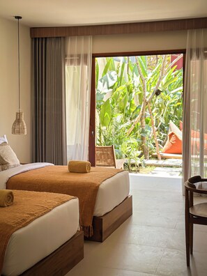 Habitación de hotel con dos camas, vistas a zonas verdes y suelo de madera.