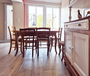 Ein Essbereich mit Holztisch und -stühlen, einem weißen Schrank mit Schubladen und einer Glasschiebetür, die zu einem Außenbereich führt.