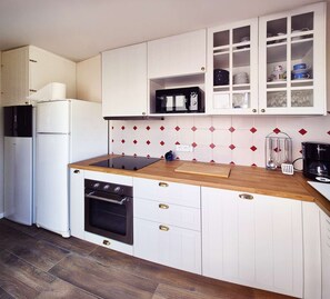 A compact kitchen with white cabinetry, a microwave, a coffee maker, and a wooden countertop. - Lucette la mouette - Les Gîtes de la Côte d'Amour (BATZ SUR MER)