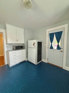 Una habitación con un refrigerador blanco, un microondas y un armario blanco.