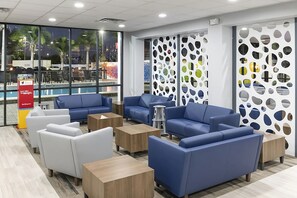 Ein moderner Loungebereich mit blauen und weißen Sofas, Holz-Beistelltischen und einer Wand mit runden Ausschnitten.
