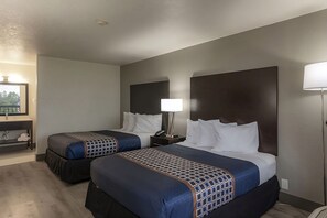 Ein Hotelzimmer mit zwei Betten, jeweils mit Kopfteil, Nachttischen und Lampen.