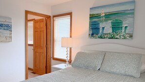 Une chambre à coucher avec un lit, un tableau, une porte et une fenêtre.