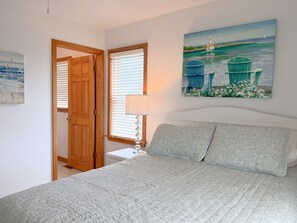 Ein Schlafzimmer mit einem Bett, einem Gemälde, einer Tür und einem Fenster.