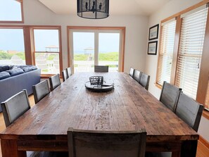 A dining area with a wooden table, chairs, and a central decorative item. - The Dune Abides - Oceanfront, Private Yard with Pool, Hot Tub, Volleyball Court (Nags Head)