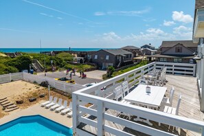 A beachside property with a pool, outdoor seating, and a view of the ocean. - The Dune Abides - Oceanfront, Private Yard with Pool, Hot Tub, Volleyball Court (Nags Head)