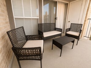 Ein Balkon mit Korbmöbeln, darunter zwei Stühle und ein Tisch.