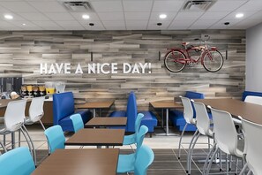 Ein moderner Essbereich mit Holzwandverkleidung, einem an der Wand befestigten roten Fahrrad und einem Schild mit der Aufschrift 'HAVE A NICE DAY!'.