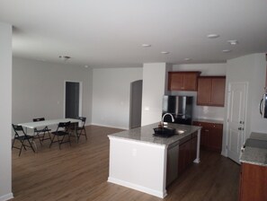A modern kitchen with a central island, wooden cabinets, and a dining area with chairs. - XYZ Hazel Green: Come Rest Awhile! (Hazel Green)