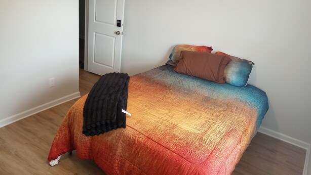 A bedroom with a bed, a door, and a white wall.