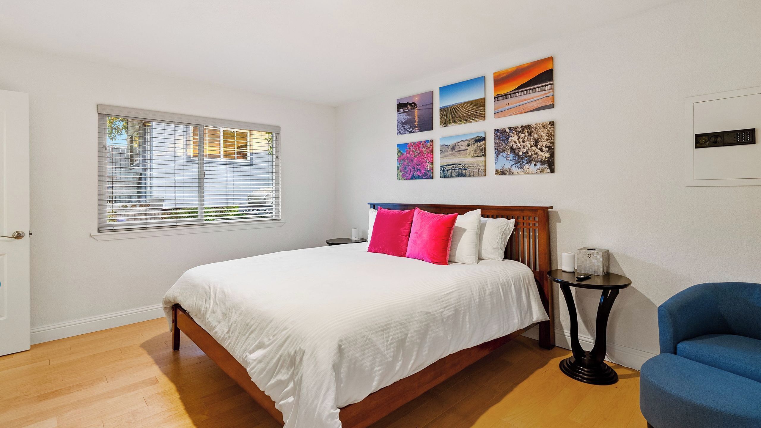 A bedroom with a bed, a bedside table, a chair, and a window with blinds.