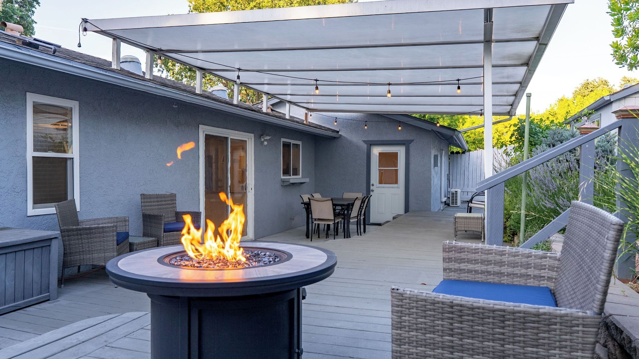 A covered patio with a fire feature, outdoor furniture, and a view of the house.