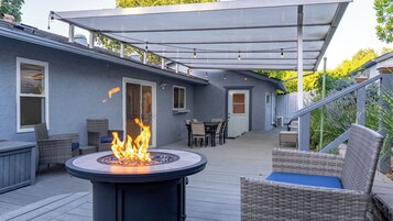 Un patio cubierto con una chimenea, mobiliario exterior y vistas de la casa.