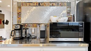 Eine Küche mit Mikrowelle, Kaffeemaschine und Mixer auf der Arbeitsfläche.