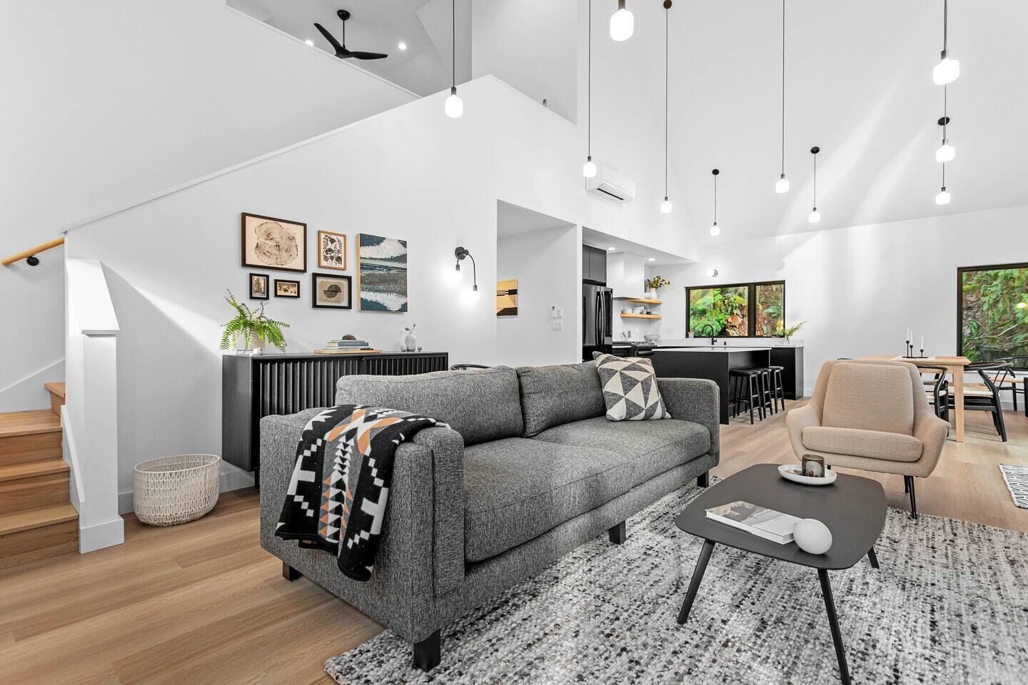 A modern living space with a grey sofa, a coffee table, and a dining area with a chair.