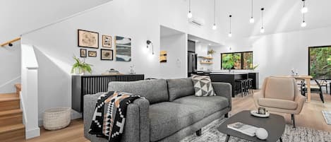 A modern living space with a grey sofa, a coffee table, and a dining area with a chair.