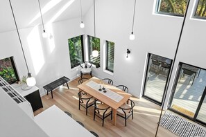 Un interior moderno con comedor, ventanas amplias y vistas al exterior.
