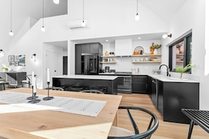 A modern kitchen with a central island, black appliances, and white cabinetry. - Modern Architect's Cabin w/ Hot Tub, Sleeps 12 (Deming)