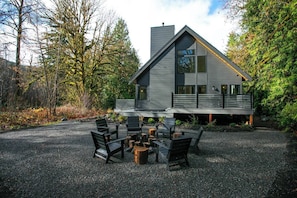 A modern house with a gravel driveway, outdoor seating area, and a large window. - Modern Architect's Cabin w/ Hot Tub, Sleeps 12 (Deming)