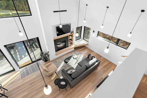 Una sala de estar moderna con chimenea, ventanas grandes y un sofá.