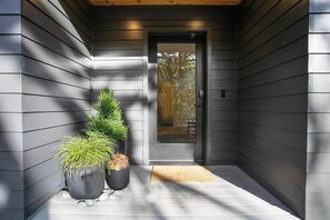 A modern exterior with a dark-colored door, potted plants, and a wooden ceiling. - Fern + Cedar Cabin | hot tub | fireplace | firepit (Deming)