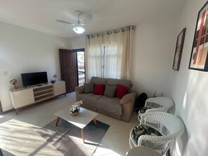 Ein Wohnzimmer mit Sofa, Couchtisch, Fernseher und Deckenventilator.