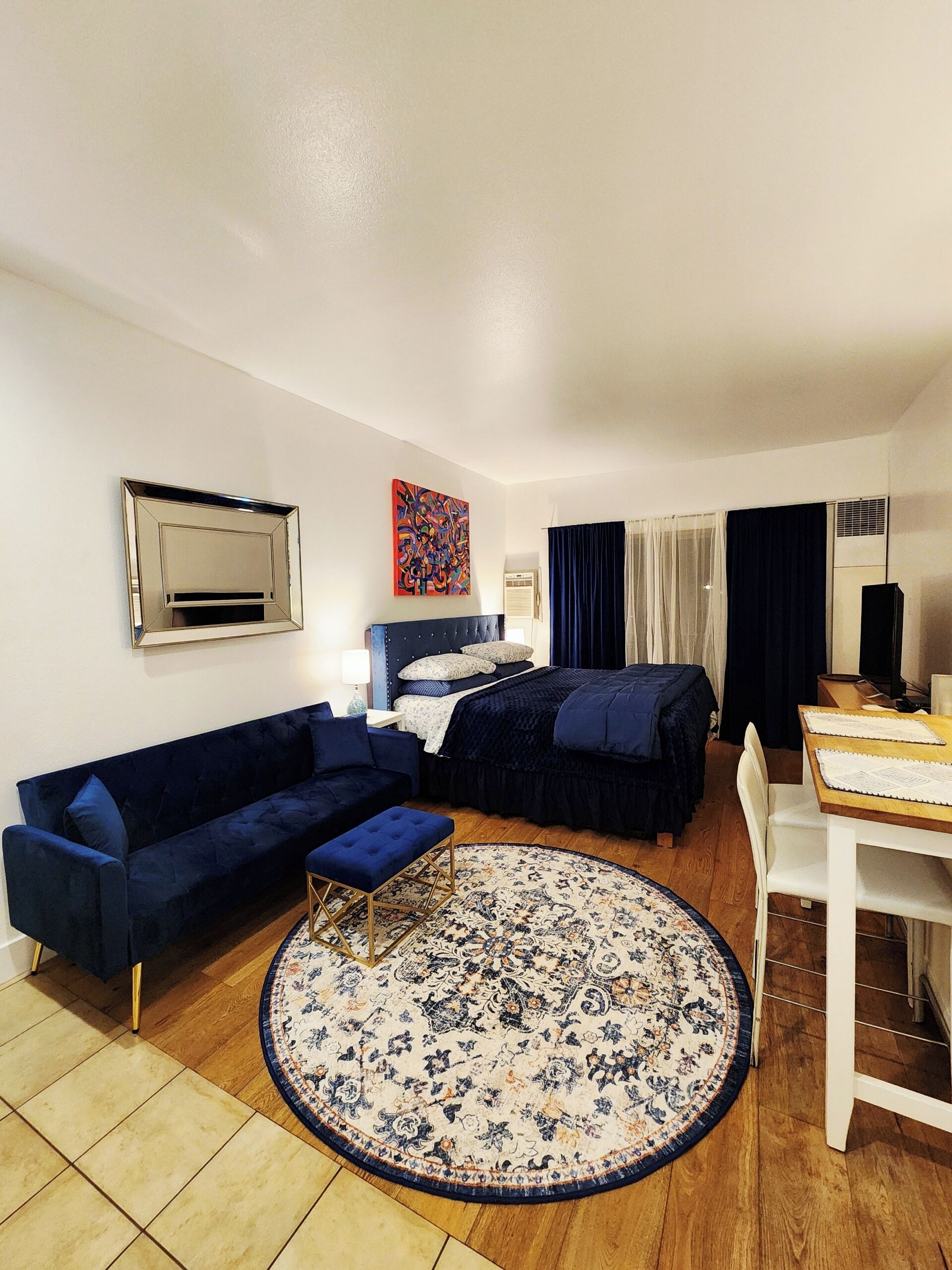 A compact hotel room with a bed, a sofa, a small table, and a TV.
