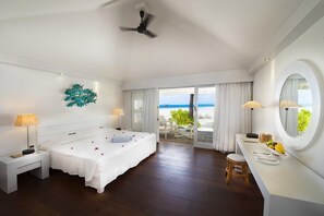 Habitación de hotel con cama, escritorio, silla, espejo redondo y vista al océano.