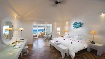 Habitación de hotel con cama, mesitas de noche, un escritorio, un espejo y vista al mar.