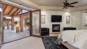 Une chambre moderne avec une cheminée, un ventilateur de plafond et un grand lit.