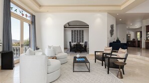 Ein geräumiges Wohnzimmer mit einem weißen Sofa, einem Couchtisch und einem Essbereich mit einem schwarzen Tisch und Stühlen.