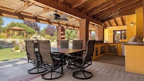 An outdoor patio with a wooden ceiling, a brick chimney, a table with chairs, and a kitchen area. - The Estate Villa at Dresser Winery by Avantstay Pool + Sauna Paso Robles (Paso Robles)