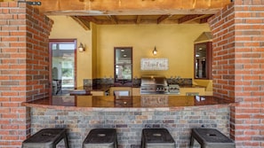 A kitchen with a brick fireplace, a gas stove, and a tiled backsplash. - The Estate Villa at Dresser Winery by Avantstay Pool + Sauna Paso Robles (Paso Robles)