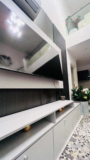 Una sala de estar moderna con televisor empotrado, gabinetes grises y piso estampado.