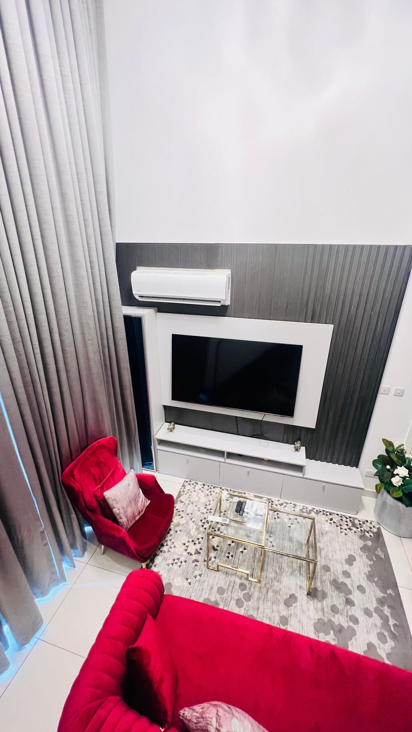 A modern living room with a flat-screen TV, red sofa, and a small coffee table.
