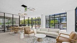 A spacious indoor area with a dining table, chairs, a sofa, and a coffee table. - Sandbar Burleigh - Ocean Delight (Gold Coast)