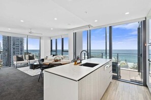 Cocina moderna con una isla grande, comedor con vistas y un balcón frente al océano.