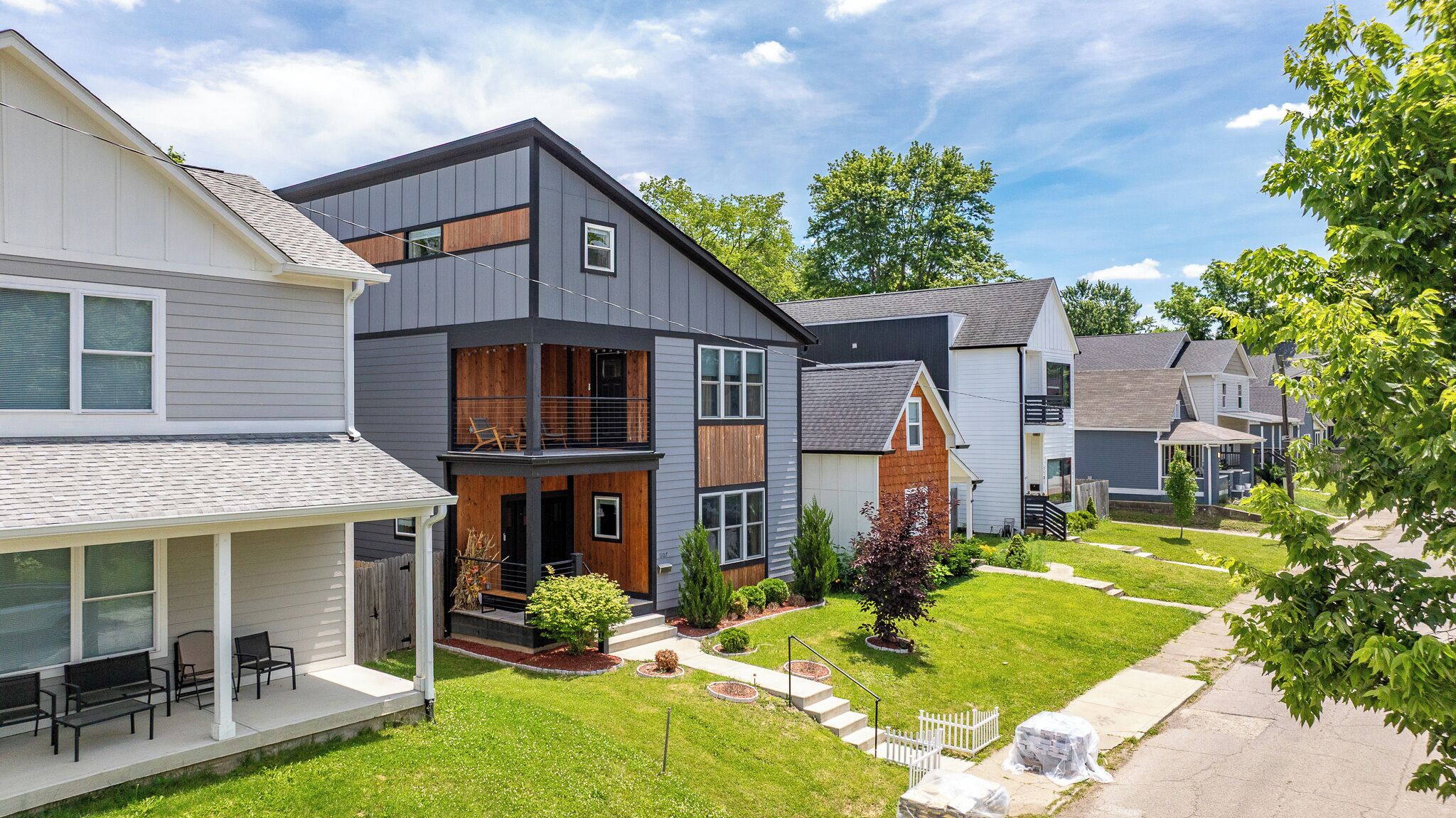 A modern residential building with a covered porch, a small garden, and a well-maintained lawn.