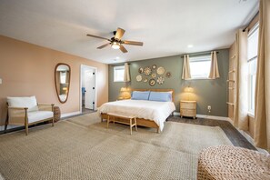 Ein Schlafzimmer mit Bett, Stuhl, Deckenventilator und einer Wand mit dekorativen Tellern.
