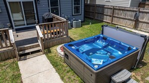 Ein Garten mit Whirlpool, einer Holzterrasse und einem Haus.